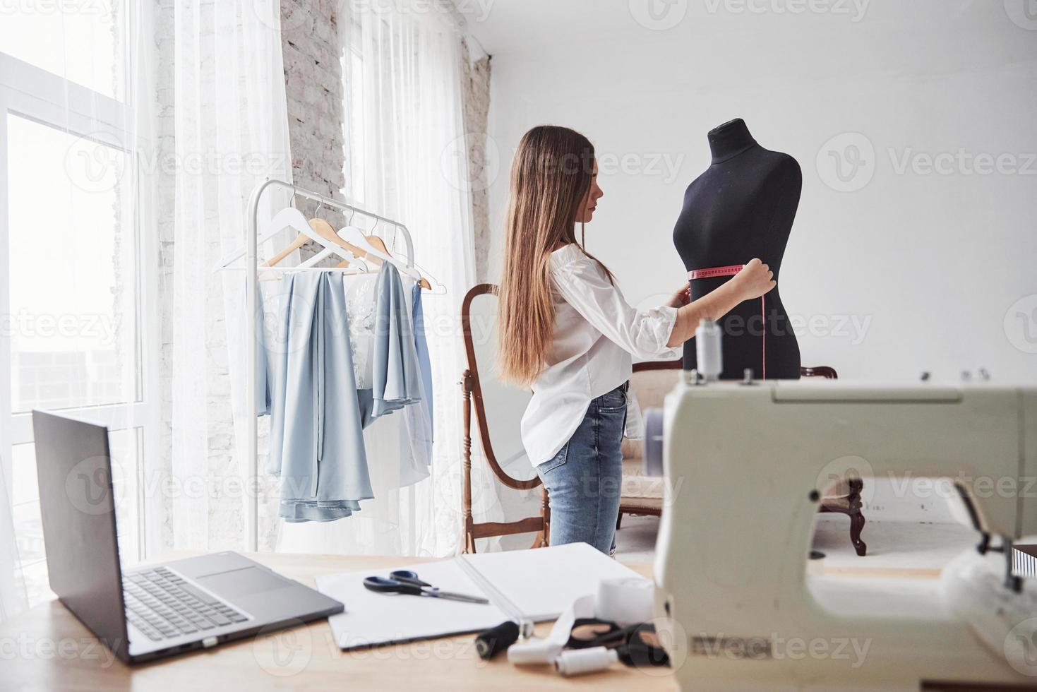 Process of measuring the width of the dummy. Female fashion designer works on the new clothes in the workshop photo