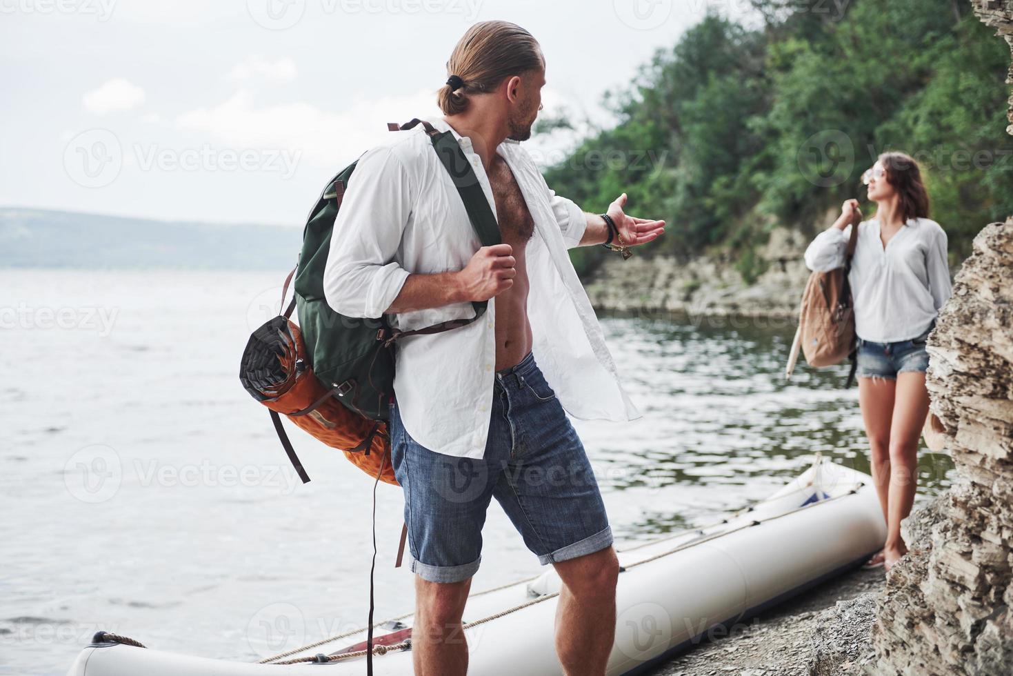 Cute young and couple on river background. A guy and a girl with backpacks are traveling by boat. Traveler summer concept photo