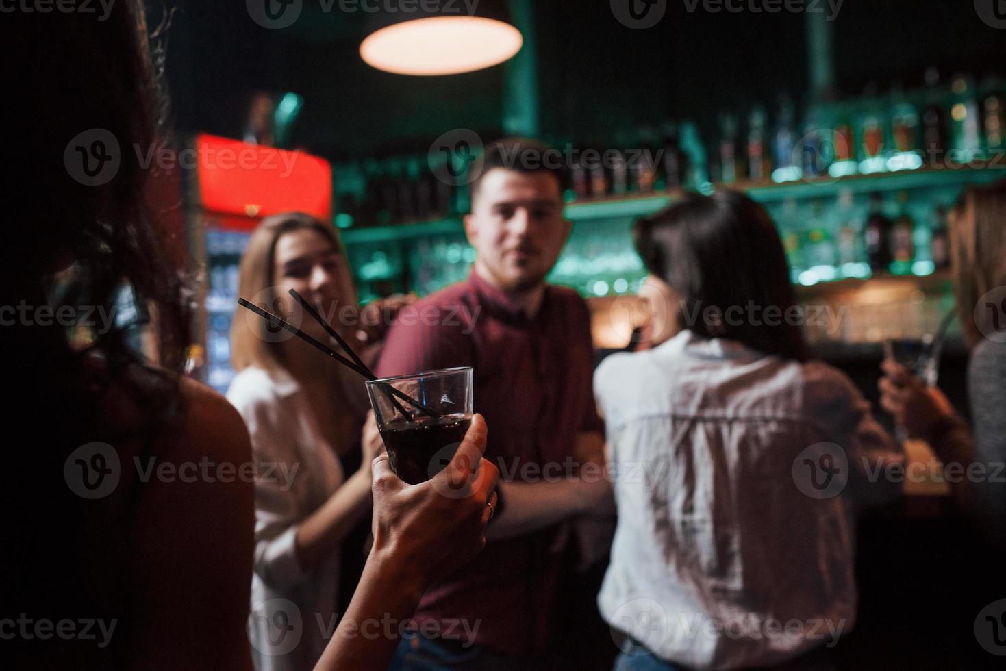 Girl with drink is coming. Beautiful youth have party together with alcohol in the nightclub photo