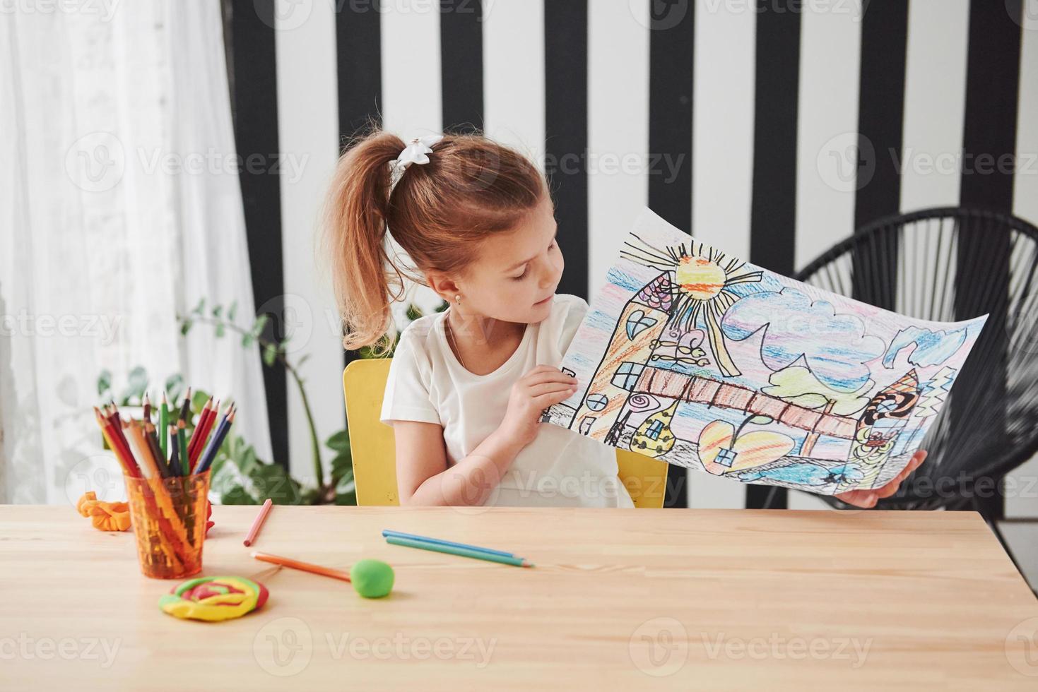 Many colorful pencils was used for this work. Cute little girl in art school shows her first paintings photo