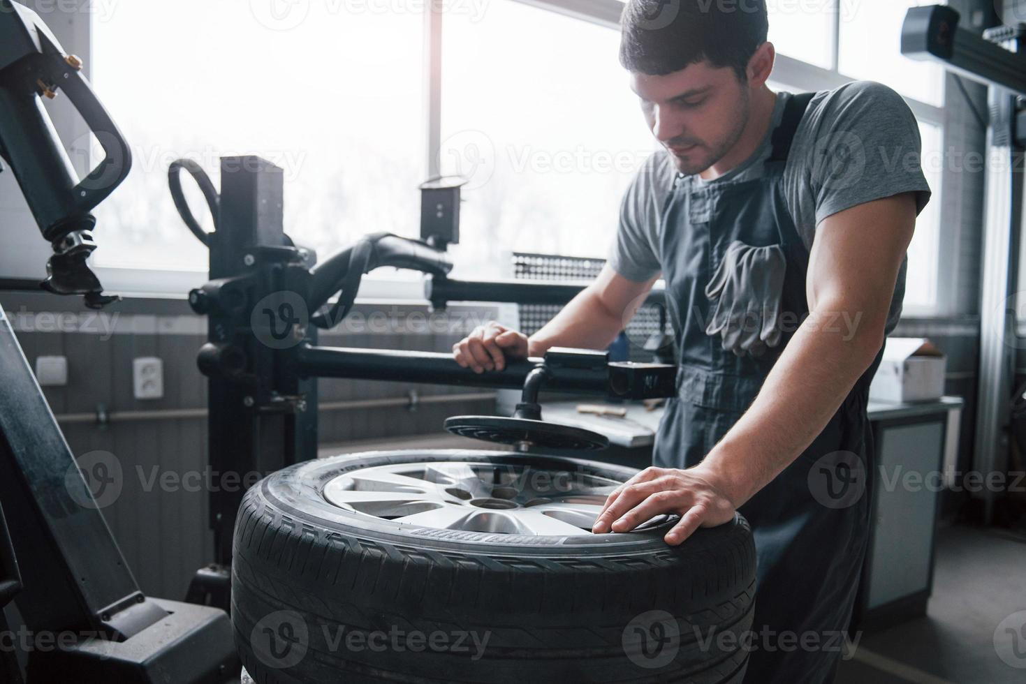 Some tweaking. Young man works with wheel's disks at the workshop at daytime photo