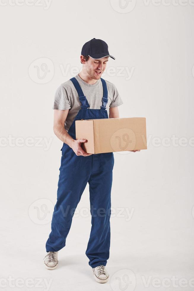 Going to the customer with order. Guy with box in hands stands against white background in the studio photo