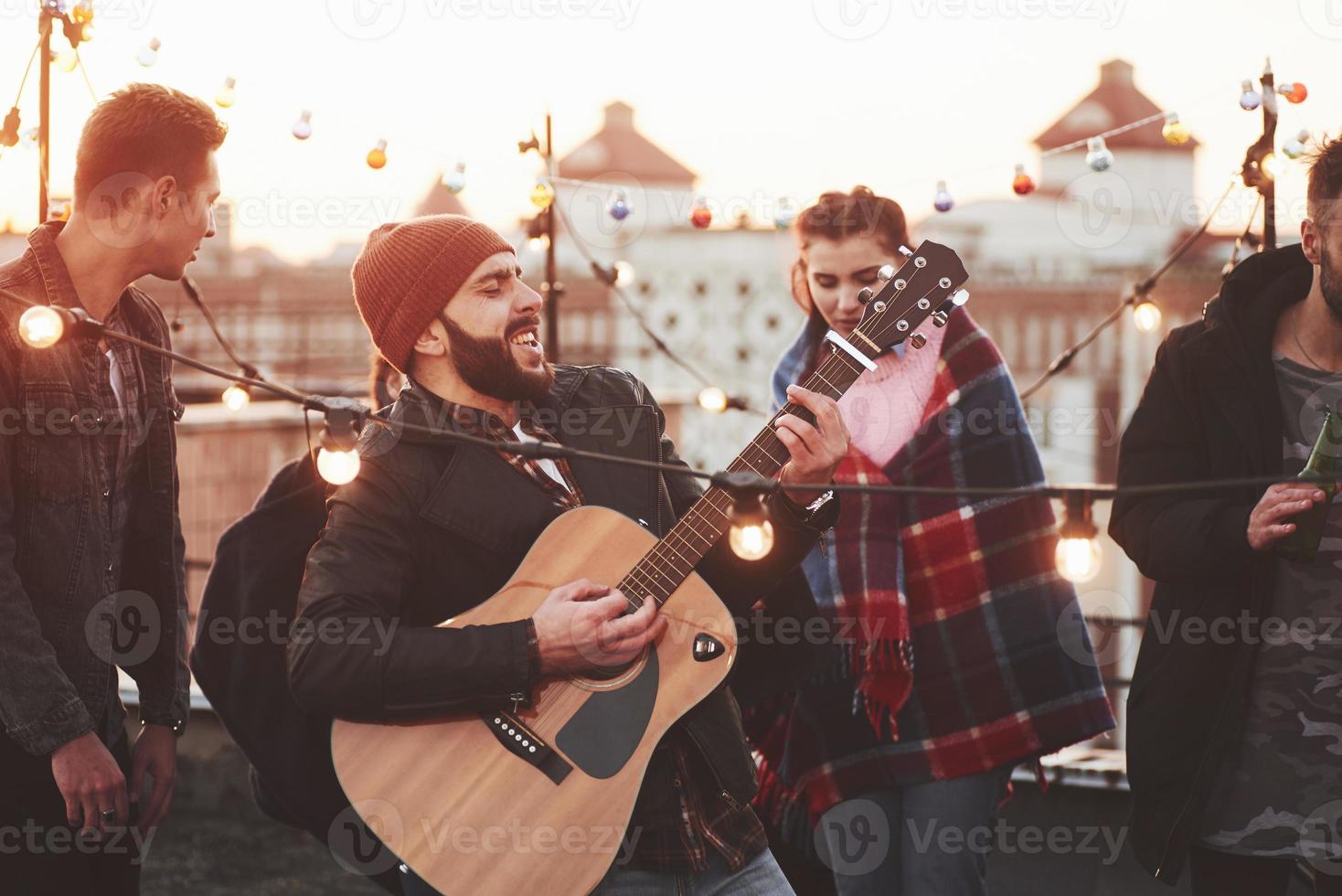 Acting like a rock star. Friends have fun at rooftop party with decorative colored light bulbs photo