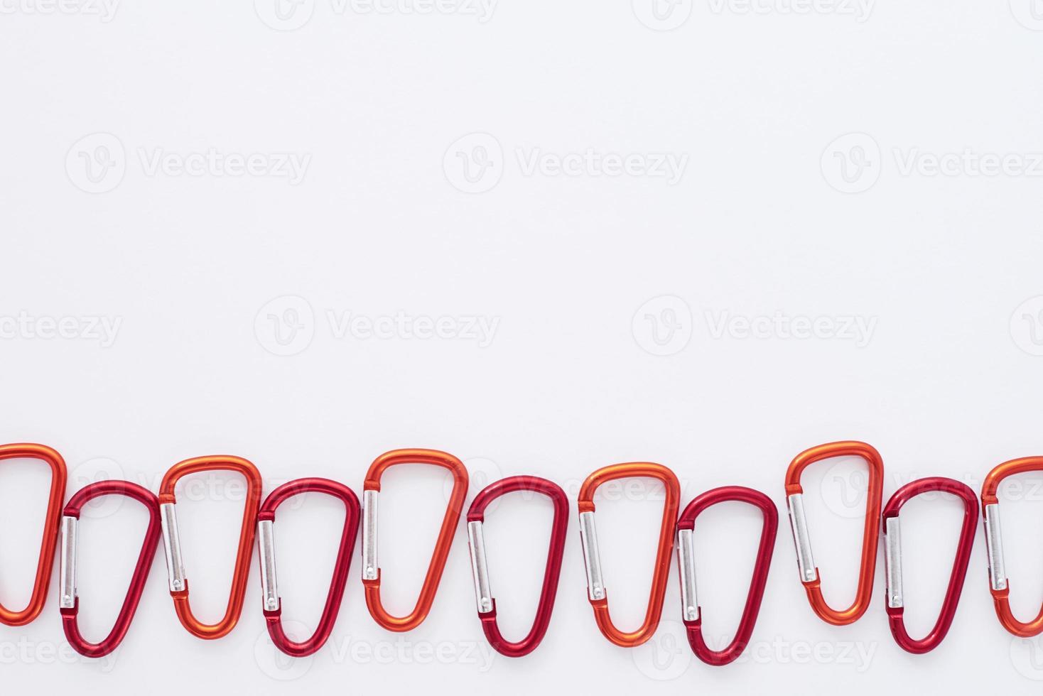 In order to each other. Many of the red colored carabiners on lying on the white table photo