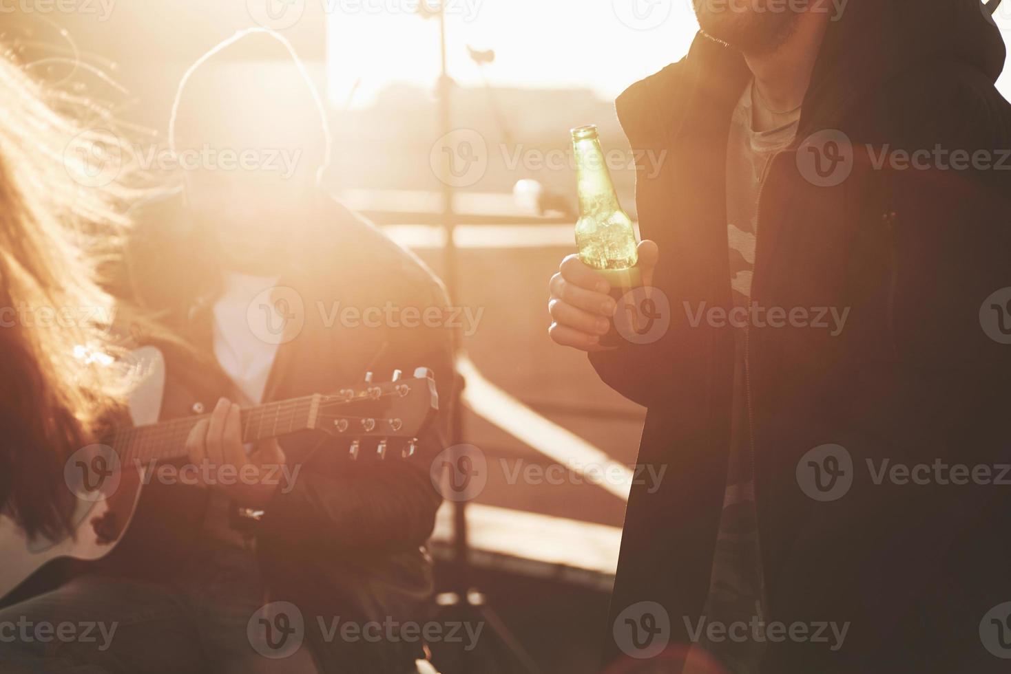 Sunshine in the autumn day. Group of friends decide to spend weekend on the rooftop with guitar and alcohol photo