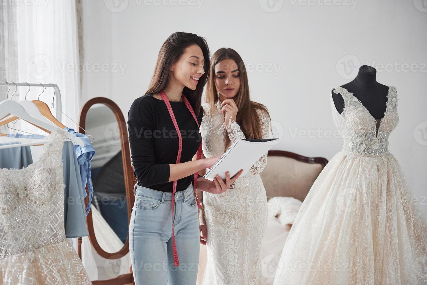 Using notepad for showing some information. The process of fitting the dress in the studio of hand crafted clothes photo