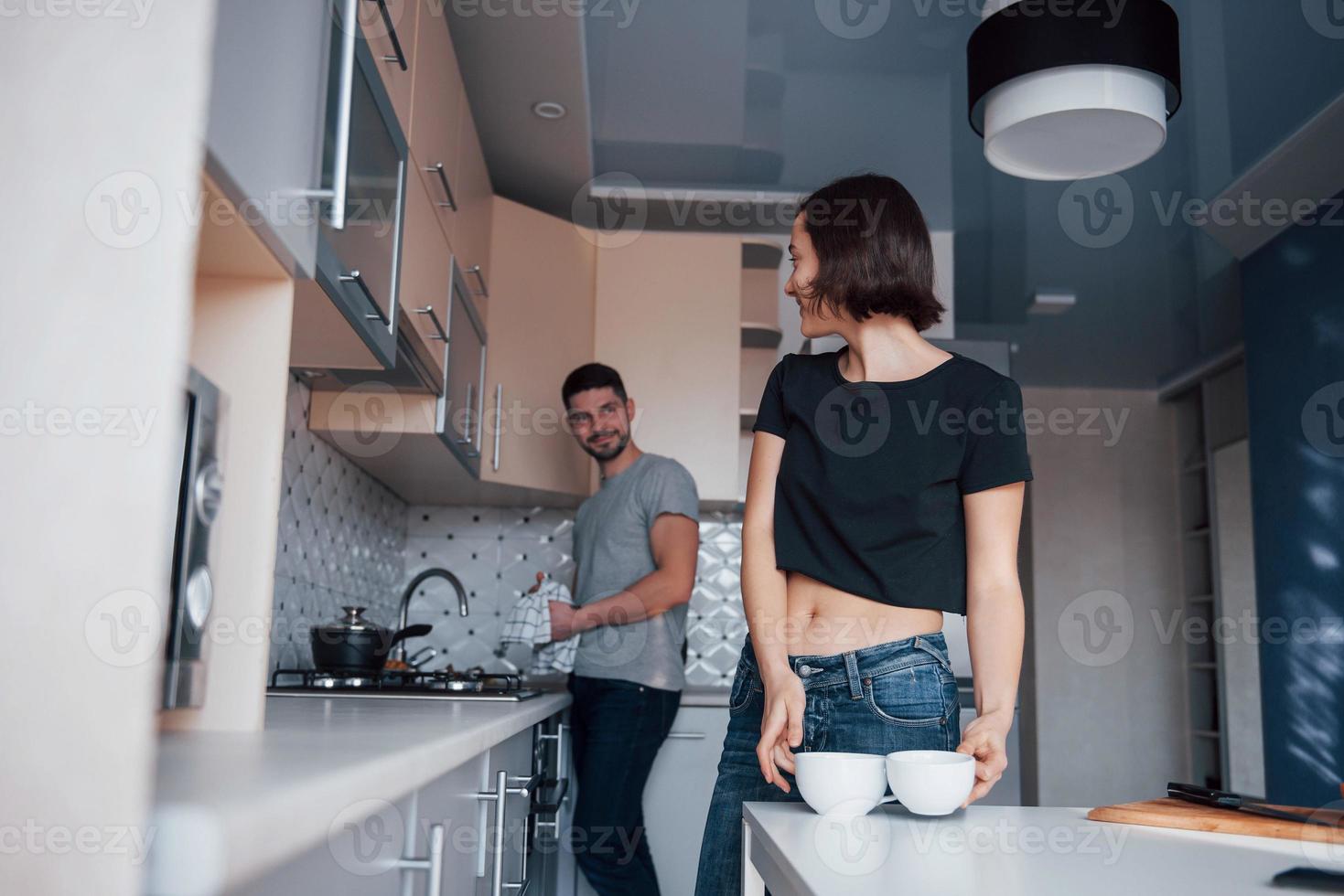 mirando el uno al otro. pareja joven en la cocina moderna en casa en su fin de semana por la mañana. foto