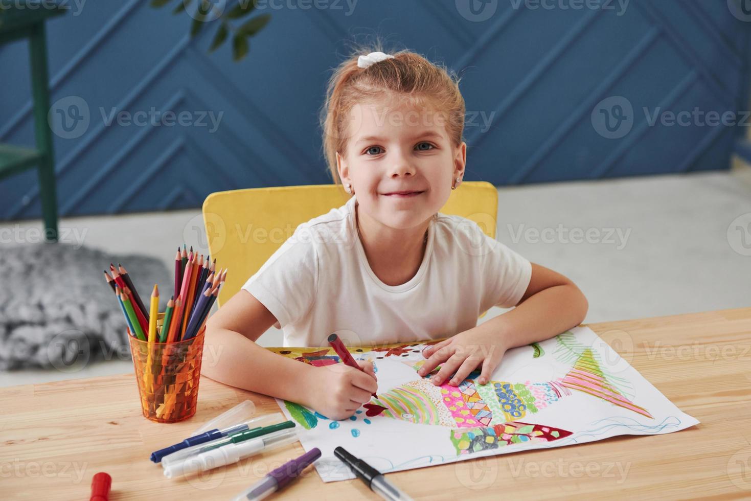 Cute little girl in art school draws her first paintings by pencils and markers photo