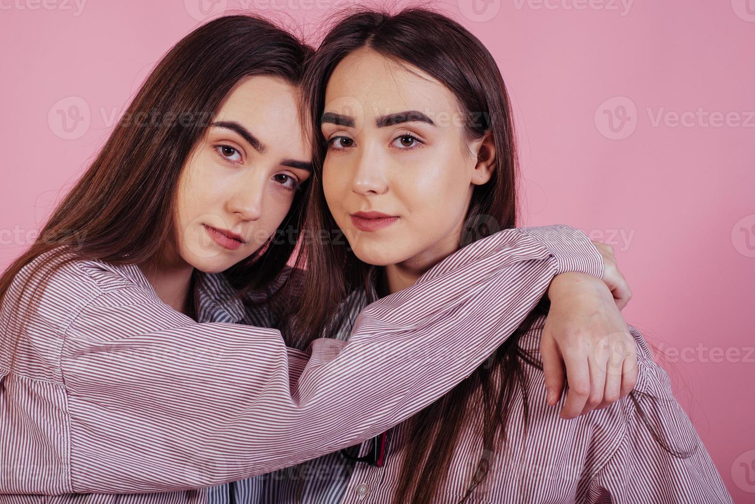 en armonía unos con otros. dos hermanas gemelas de pie y posando en el estudio con fondo blanco foto