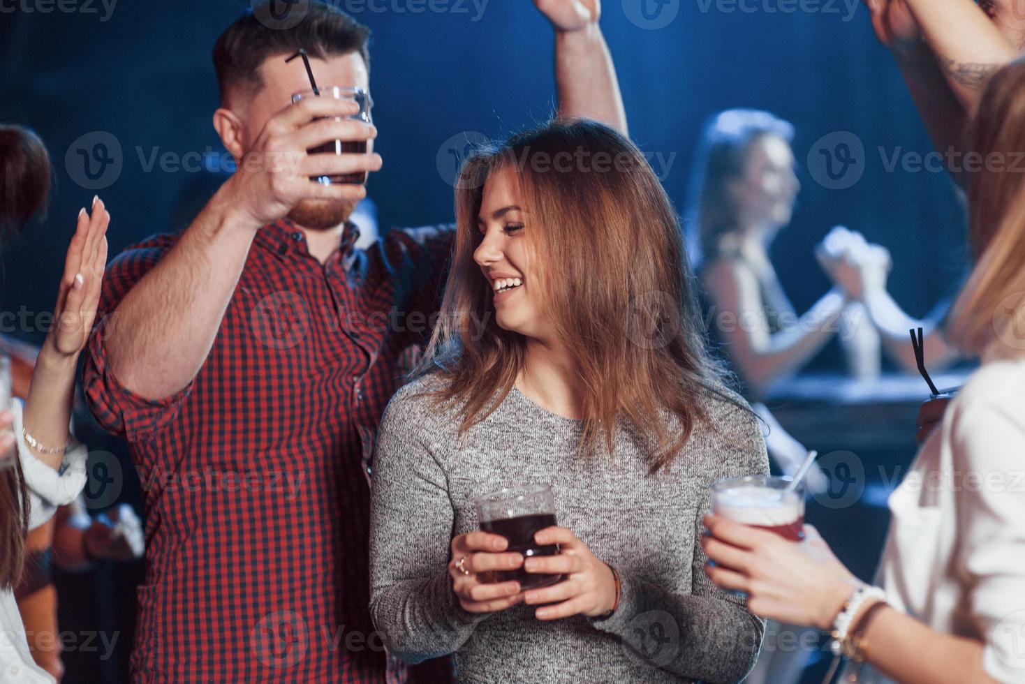 Smiling and moving. Happy people dancing in the luxury night club together with different drinks in their hands photo