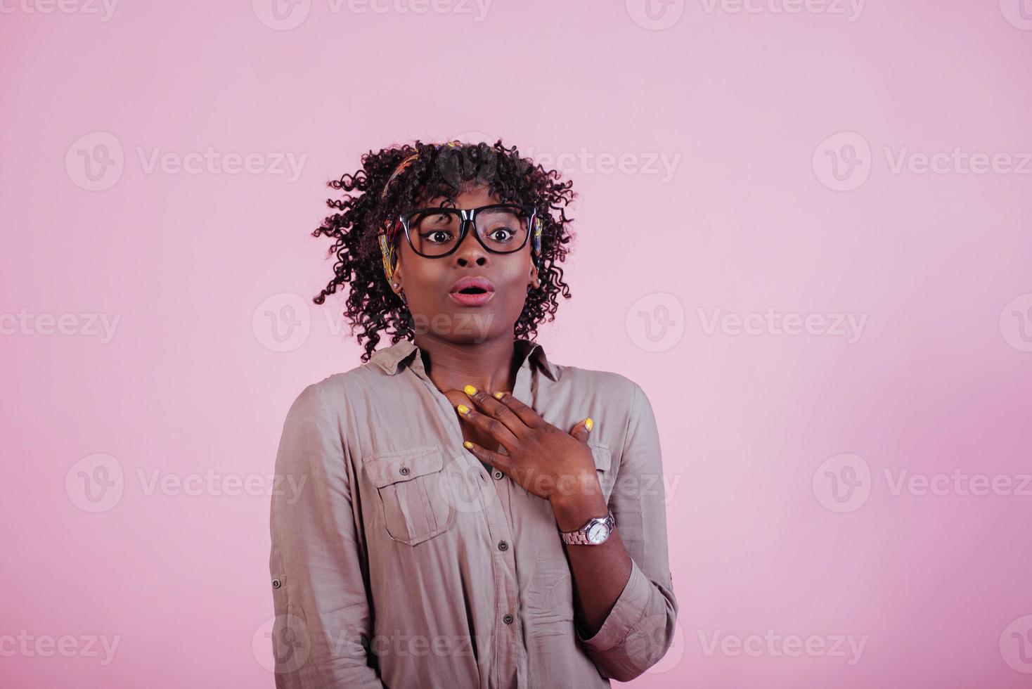 Shows shocking expression. Attractive afro american woman in casual clothes at pink background in the studio photo