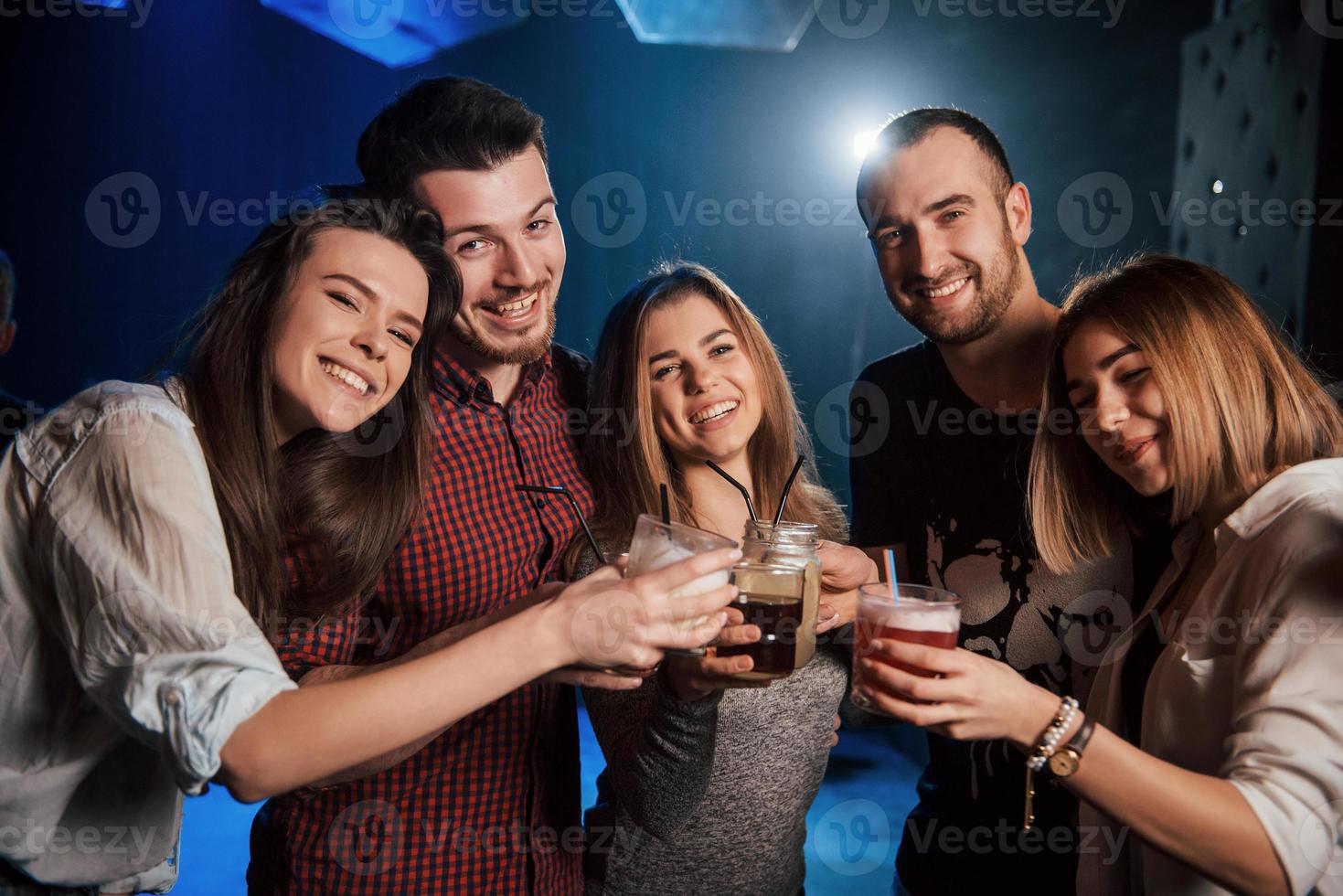 Tastes drinks. Group of young friends smiling and making a toast in the nightclub photo