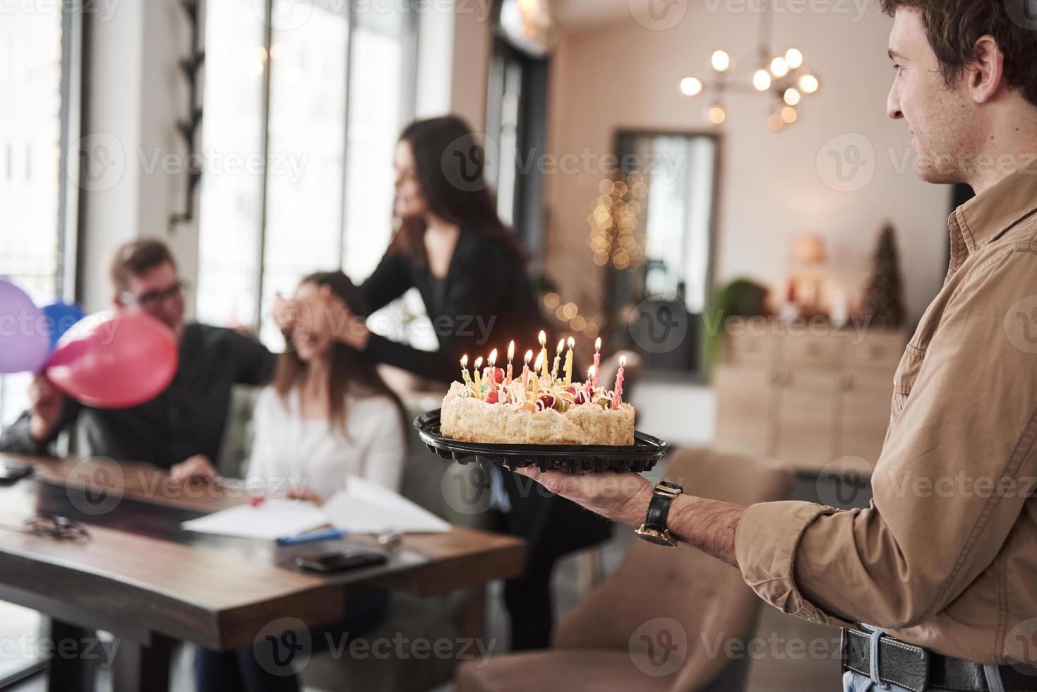 vista de cerca del delicioso pastel con velas. uno de los empleados tiene cumpleaños hoy. compañeros de trabajo amistosos decide hacer una sorpresa para ella foto
