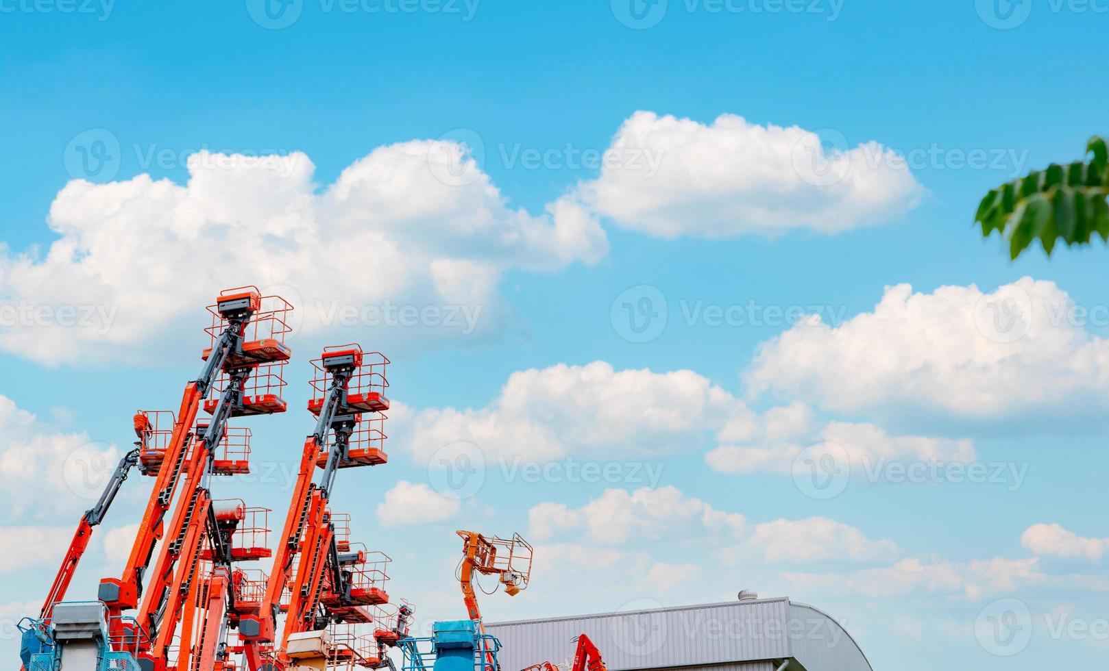 Articulated boom lift. Aerial platform lift. Telescopic boom lift against blue sky. Mobile crane parked at parking area for rent. Hydraulic boom lift at parking lot of crane dealership sale office. photo