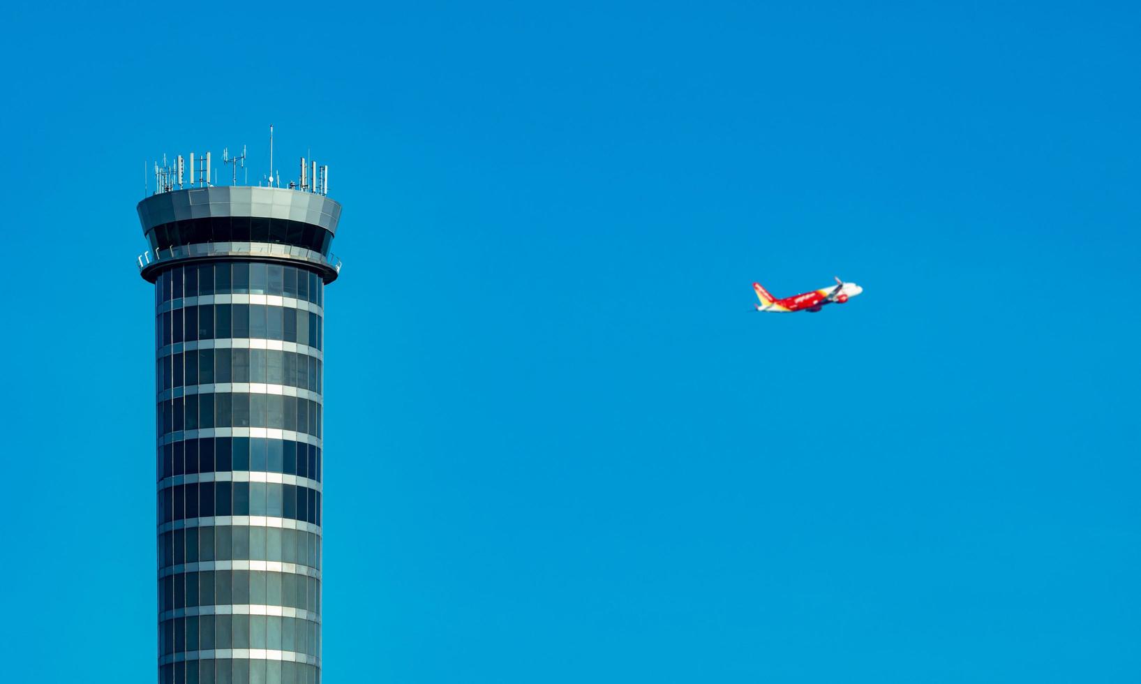 Air traffic control tower in the airport with international flight plane flying on clear blue sky. Airport traffic control tower for control airspace by radar. Aviation technology. Flight management. photo