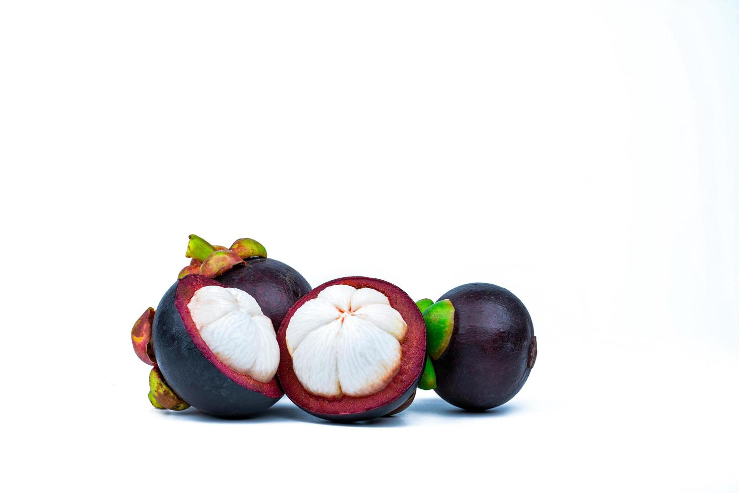 Two whole purple mangosteen and two cross section isolated on white background. Tropical fruit from Thailand. The queen of fruits. Asia fresh fruit market. Natural source of tannin and xanthones photo