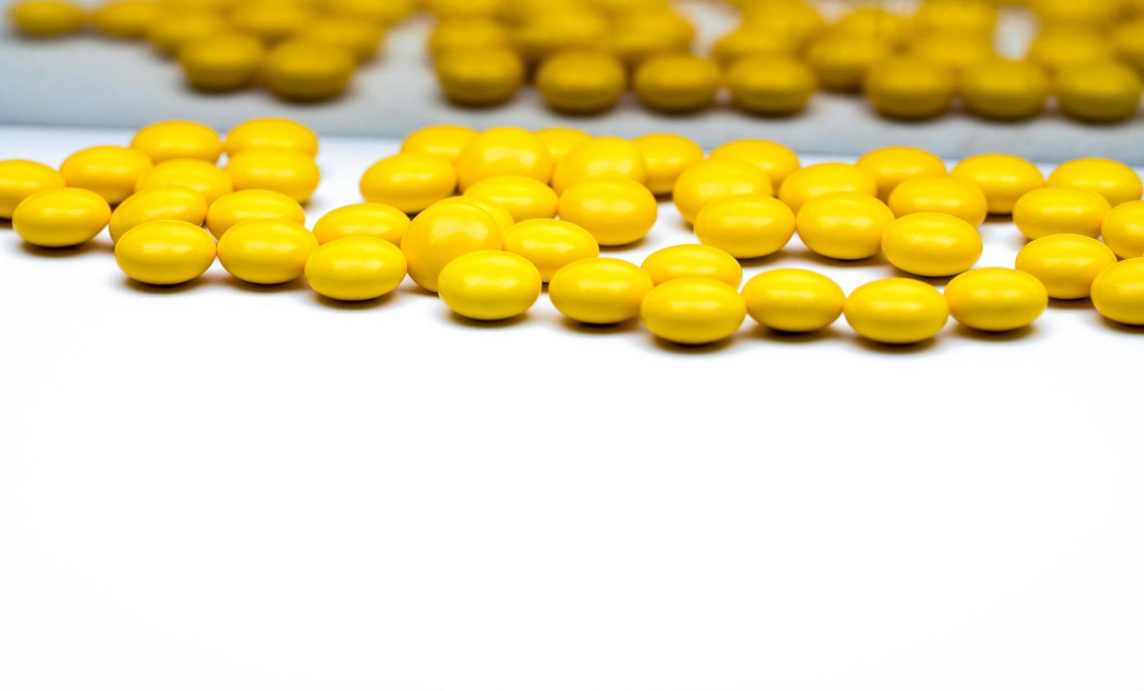 Macro shot detail of yellow round sugar coated tablets pills on blurred tablets pills background with copy space for text. photo