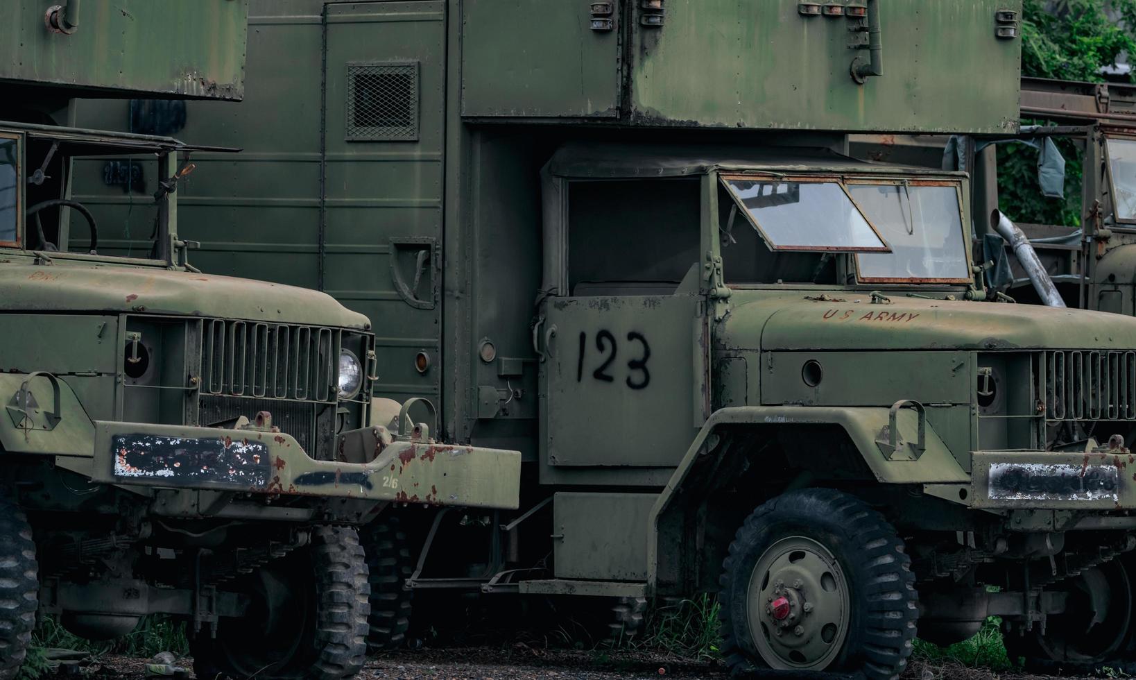 la vista frontal del viejo camión verde militar destrozado tendrá un neumático desinflado viejo. camión militar oxidado abandonado. camión abandonado deteriorado con texto del ejército estadounidense en el capó. coche a prueba de balas estacionado en el estacionamiento. foto