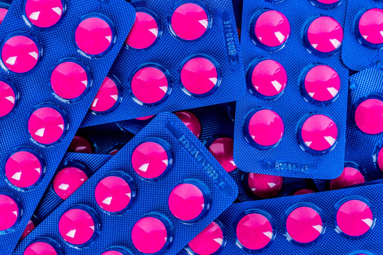 Pink tablets pill in blue blister pack isolated on white background. Painkiller medicine. Pharmaceutical industry. Medicine for treat migraine headache, fever, toothache. Pharmacy drugstore products. photo