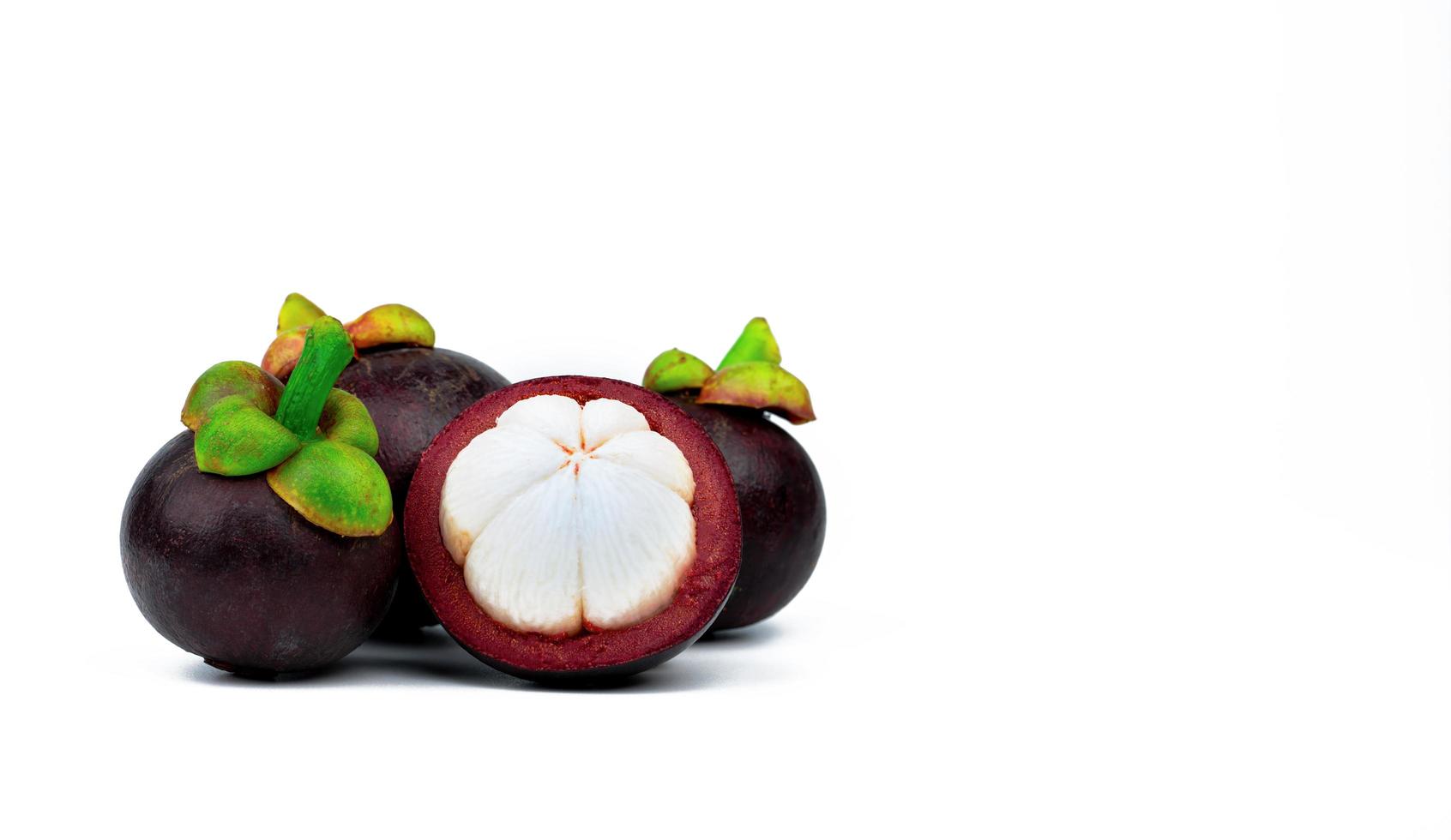 Three whole purple mangosteen and another cross section isolated on white background. Tropical fruit from Thailand. The queen of fruits. Asia fresh fruit market. Natural source of tannin and xanthones photo