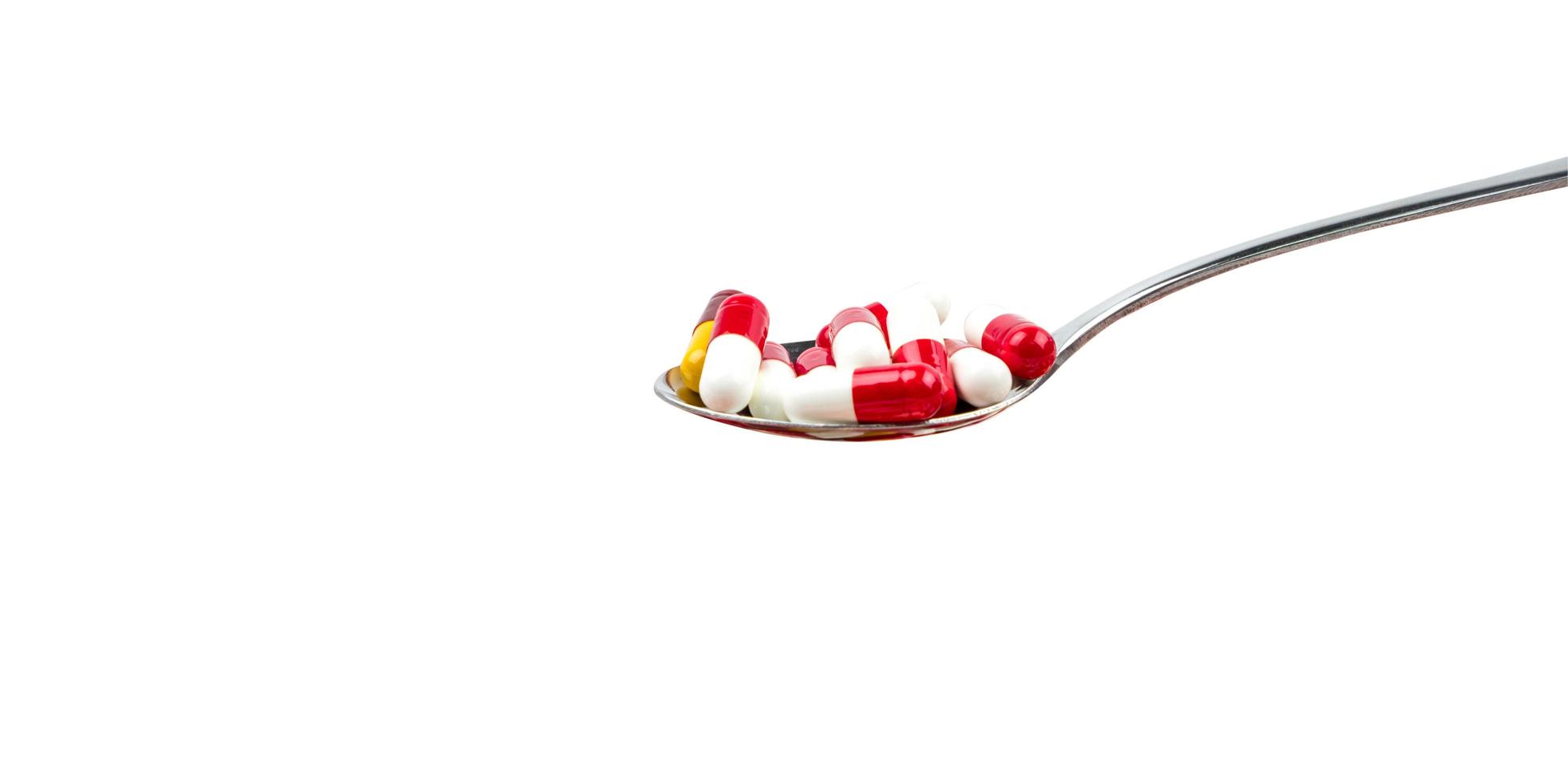 Antibiotic capsule pills in stainless steel spoon isolated on background with copy space. Drug resistance concept. Antibiotics drug use with reasonable and global healthcare concept. photo