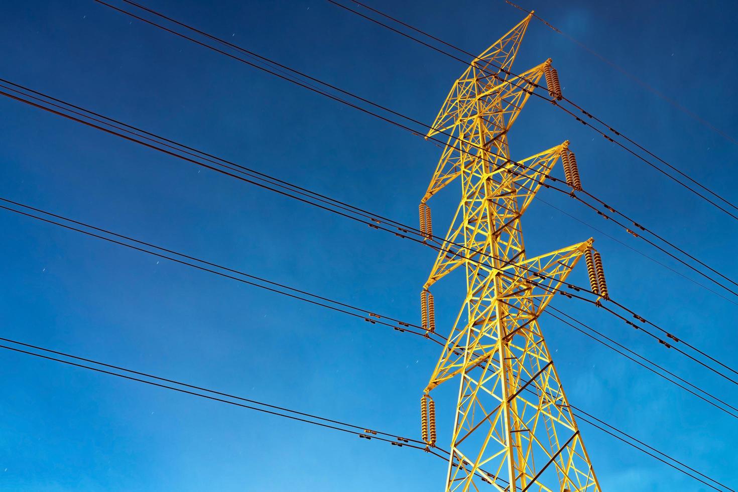 High voltage electric pole and transmission lines in the evening. Electricity pylons at night. Power and energy. Energy conservation. High voltage grid tower with wire cable at distribution station. photo