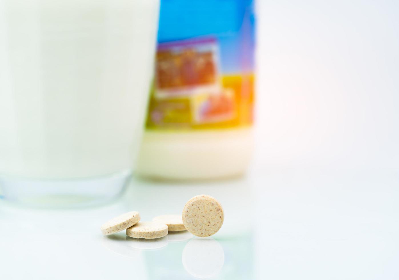 Sweetened flavored milk tablets and one glass of milk and milk bottle on white background. Calcium food products from cow milk for healthy bone. photo