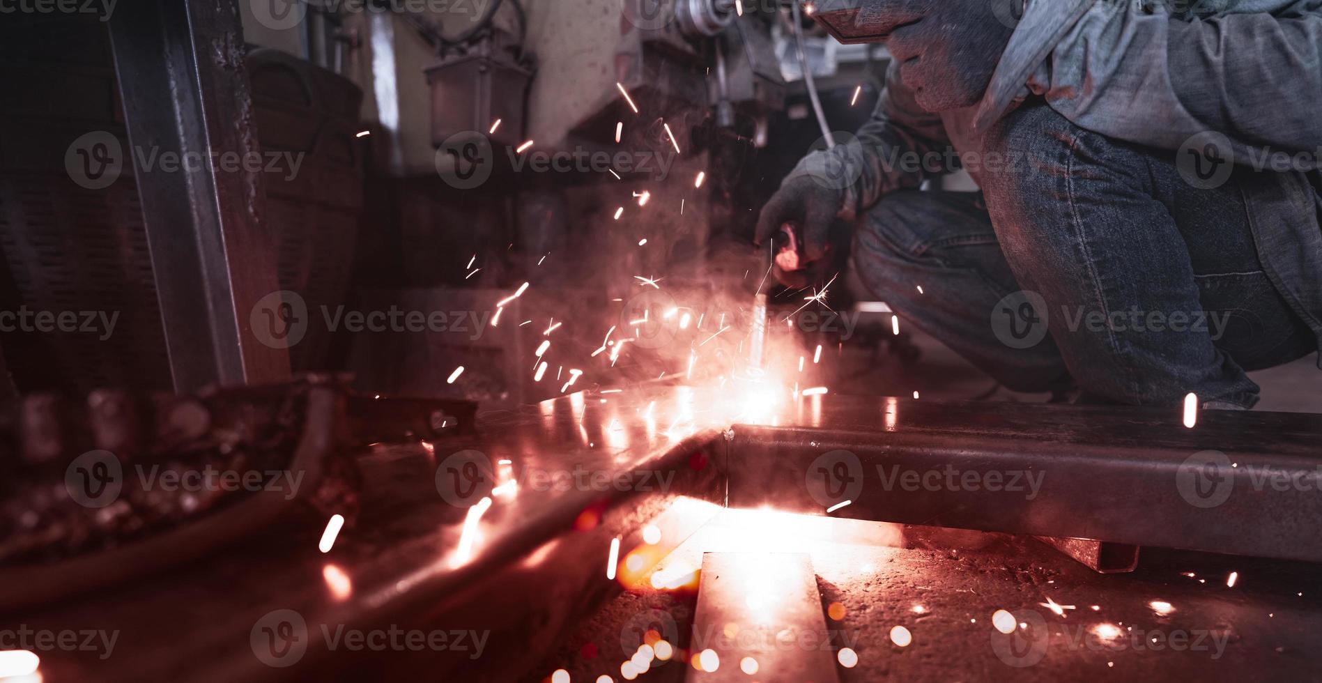 soldador de soldadura de metal con máquina de soldadura por arco de argón y tiene chispas de soldadura. un hombre usa máscara de soldadura y guantes protectores. seguridad en el lugar de trabajo industrial. soldador trabajando con seguridad. industria metalúrgica. foto