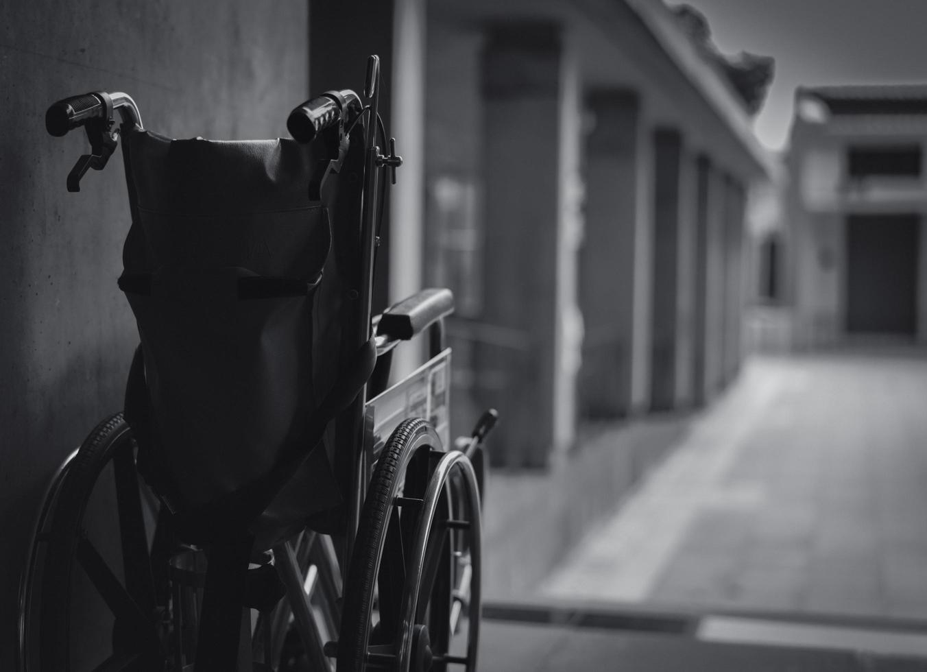 Wheelchair folded beside the wall. Sad news at the hospital concept. Depression with aging society. Lonely empty wheelchair. Medical equipment for service patient and assistant disabled elderly people photo