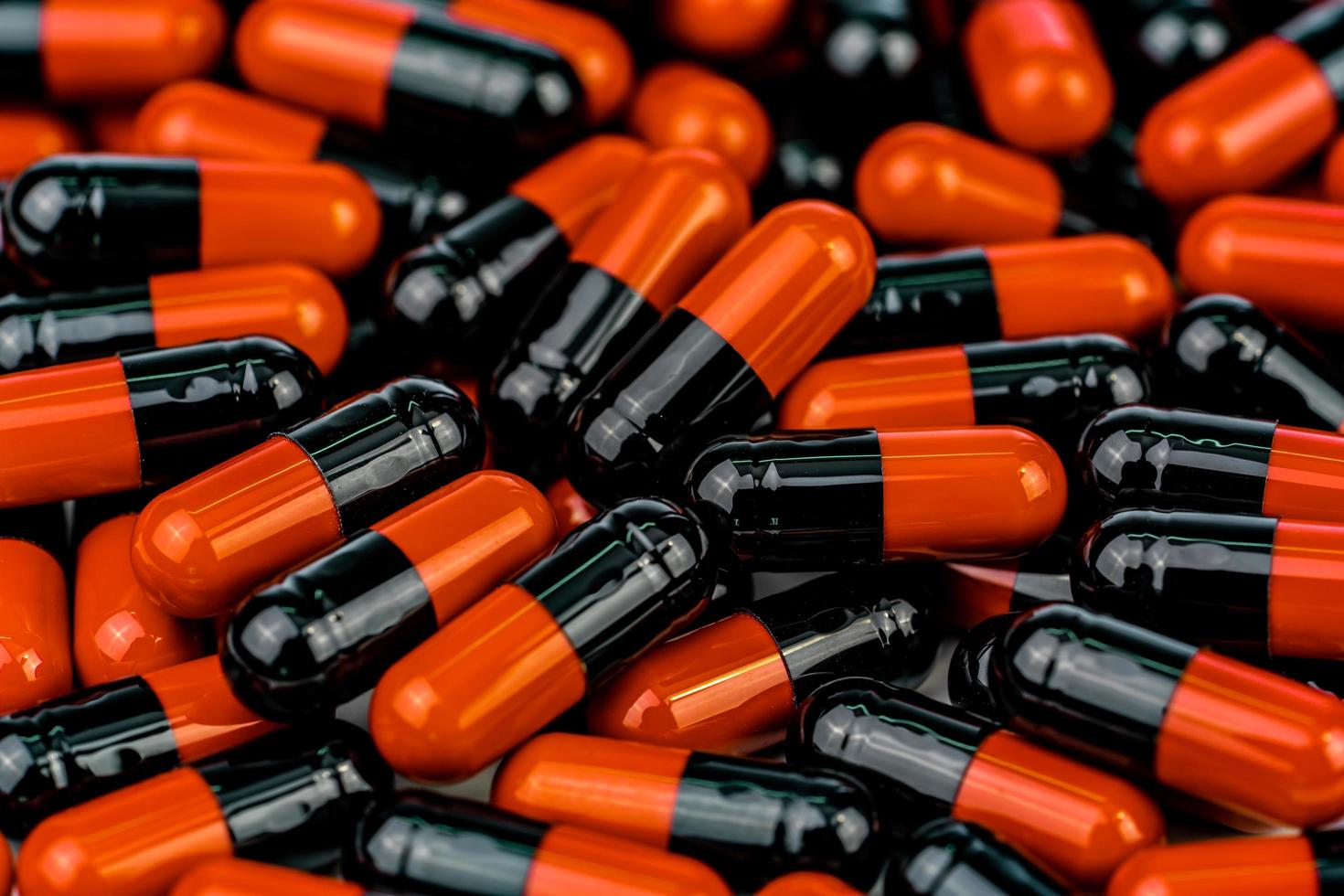 Pile of orange-black capsule pills. Antibiotics resistance. Drug use with reasonable. Global healthcare concept. Antibiotics drug resistance. Antimicrobial capsule pills. Pharmaceutical industry. photo