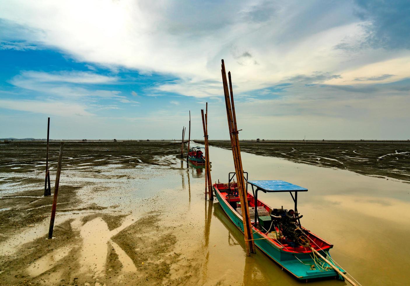 Fisherman's boat parked at coastal mud flat at tide. Landscape of sea and beautiful blue sky and white clouds. Mud beach. photo