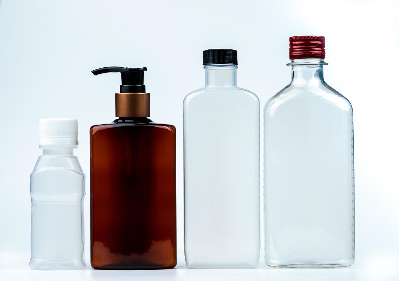 Empty plastic and glass bottle with cap and pump with black label isolated on white background. Pharmaceutical products bottle packaging. photo