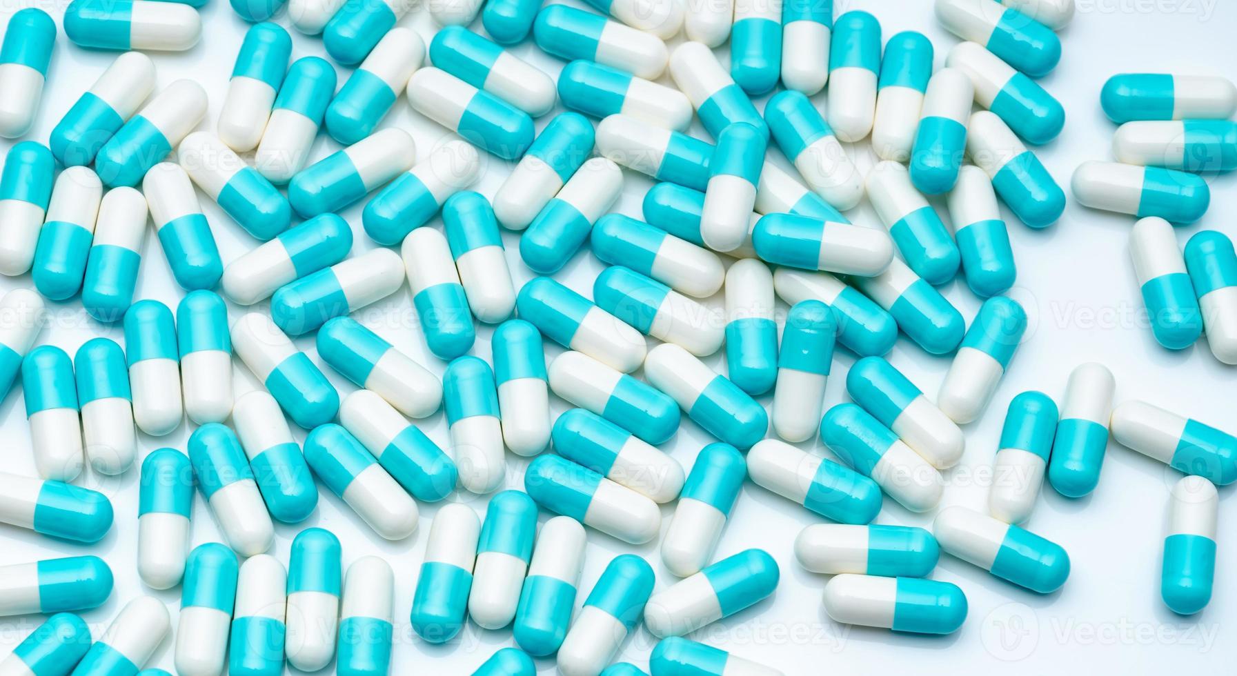 Blue and white capsule pills on white background. Pharmaceutical industry. Blue pastel color capsule pills spread on white table. Pharmaceutics background. Healthcare and medicine. Pharmacy products. photo