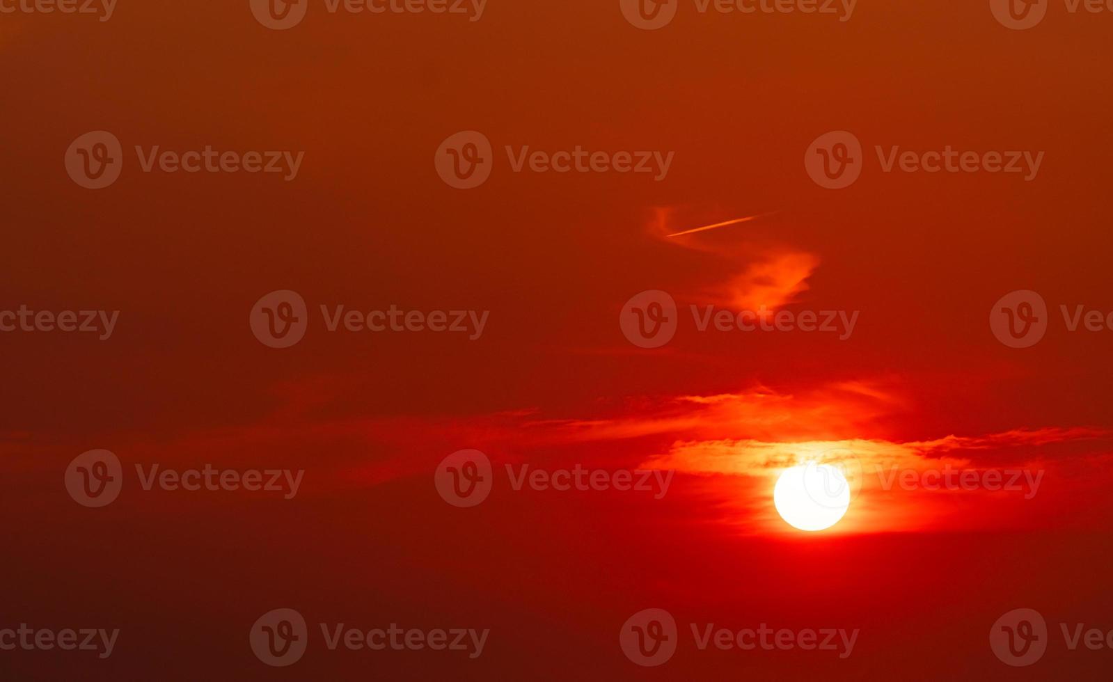 Beautiful red sun at sunset. Red sunset sky. The sun is obscured by some clouds at sunset. Big sun in the evening. Blood sky. Heat and hot weather. Dramatic sun light. Background for majestic. photo