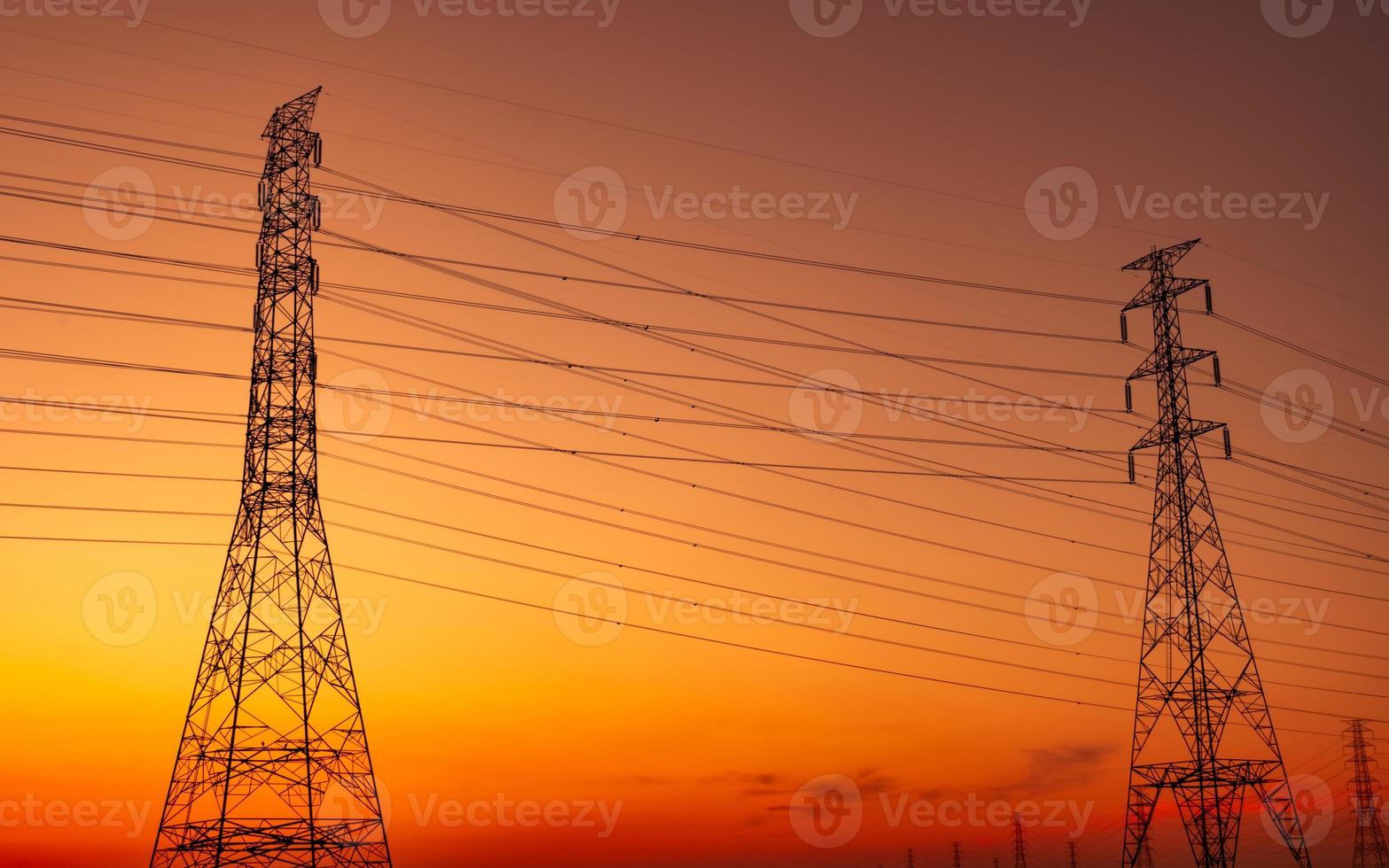 pilón eléctrico de alto voltaje y cable eléctrico con cielo al atardecer. postes de electricidad concepto de fábrica de soporte de energía y energía. torre de red de alto voltaje con cable de alambre. hermoso cielo de puesta de sol rojo-naranja. foto