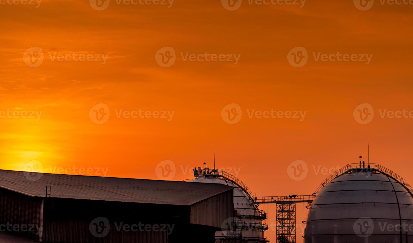 Industrial gas storage tank. LNG or liquefied natural gas storage tank. Red and orange sunset sky. Spherical gas tank in petroleum refinery. Above-ground storage tank. Natural gas storage industry. photo