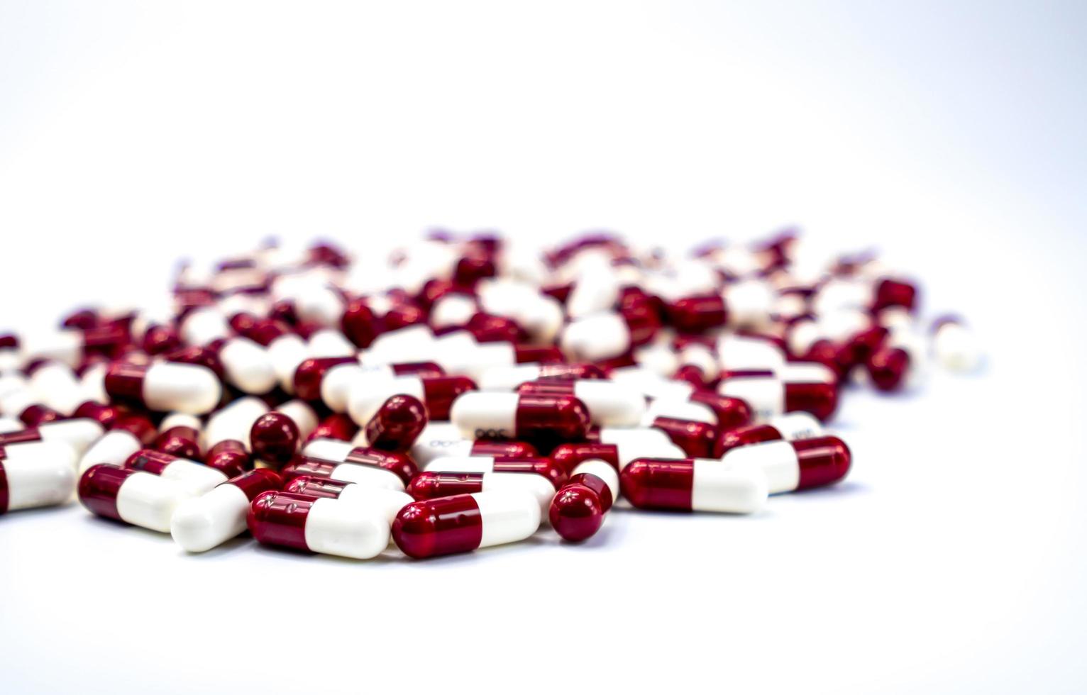 Selective focus red and white capsule pills on white background. Gemfibrozil is used to treat high cholesterol and triglyceride levels in people with pancreatitis. Pharmaceutical industry. Pharmacy. photo