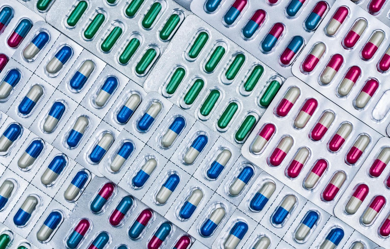 Full frame of colorful antimicrobial capsule pills. Quality control error in pharmaceutical manufacturing. Blister pack missing one capsule of antibiotic pill. Drug resistance concept. photo