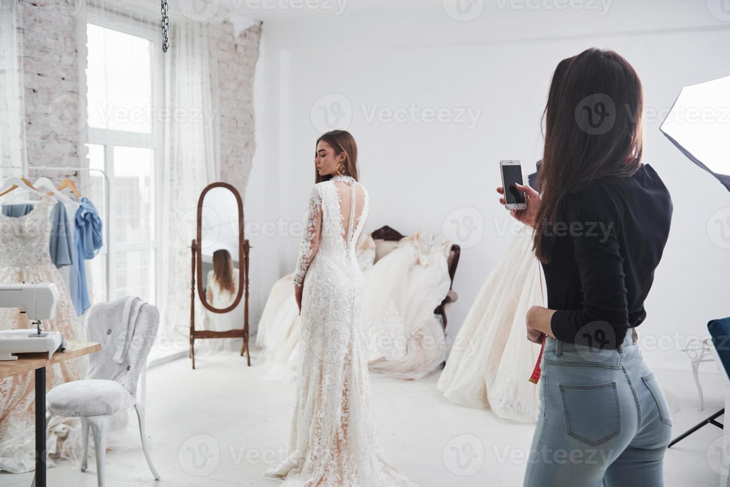 Friend takes a photo to show how it looks from behind. The process of fitting the dress in the studio of hand crafted clothes