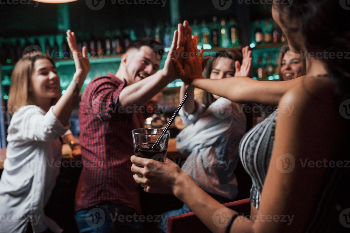 dar los cinco altos. hermosos jóvenes tienen fiesta junto con alcohol en la discoteca foto