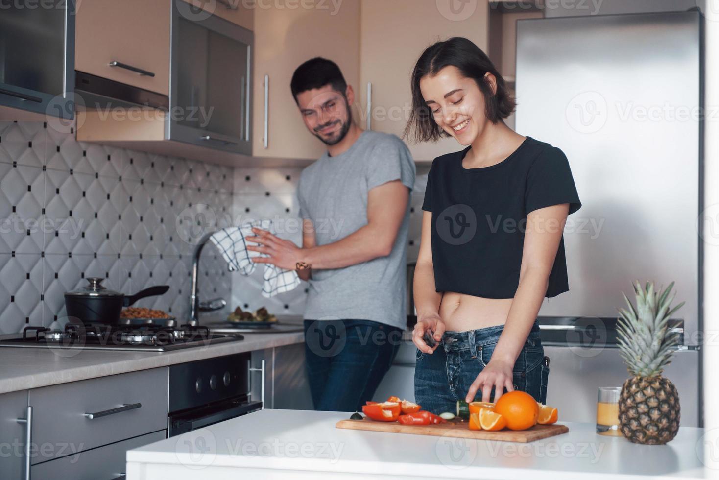 Making salad and dessert. Young couple in the modern kitchen at home at their weekend time in the morning photo