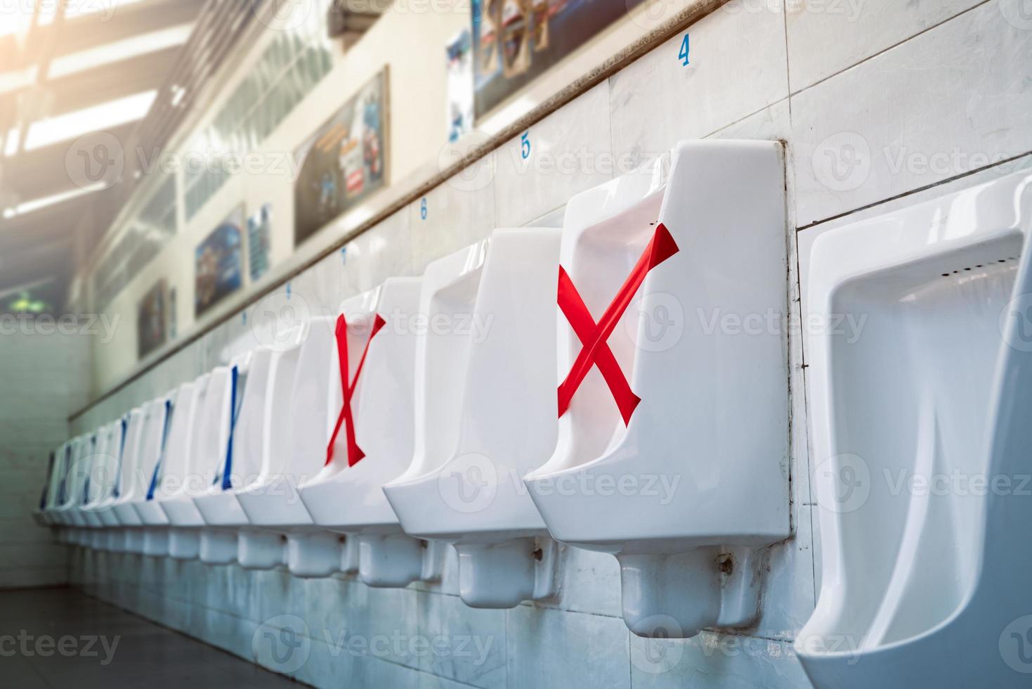 White ceramic urinals in men public toilet. Social distancing in men restroom to prevent coronavirus pandemic. Man bladder health with urinary incontinence problem. Urine infections. Male latrine WC. photo