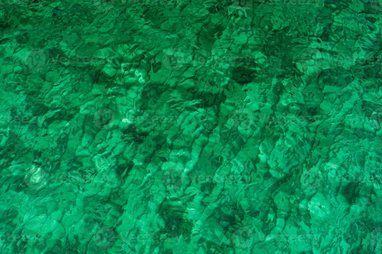 Green abstract texture background of emerald green sea water. Top view of green sea water with unique pattern. Green background. Sea water wave surface at coast. Turquoise water at shallow sea. photo