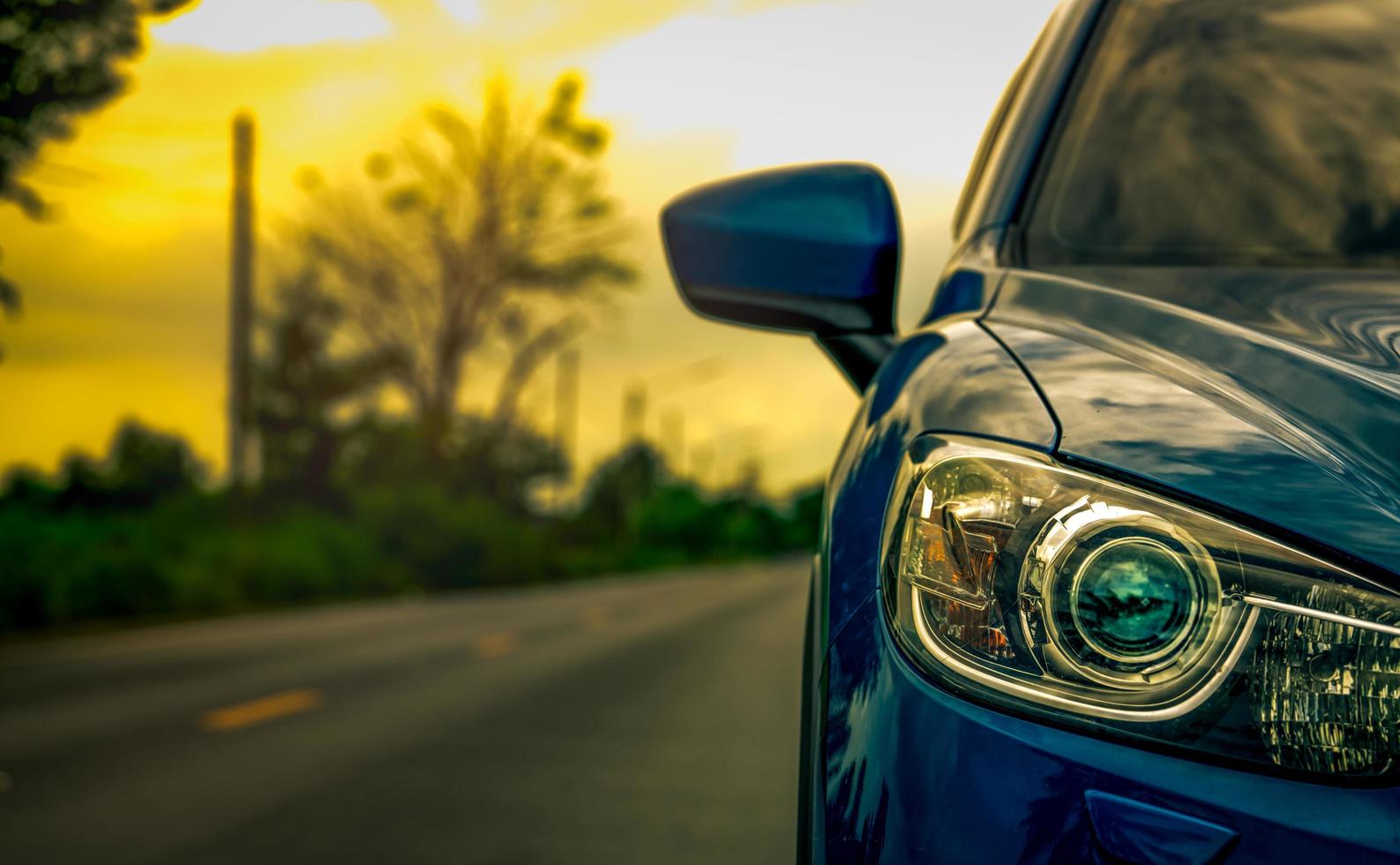 vista frontal de un lujoso camión suv compacto azul con diseño deportivo y moderno estacionado en una carretera asfaltada al atardecer. concepto híbrido de automóvil y automóvil. viaje por carretera y conducción de automóviles para viajar. foto