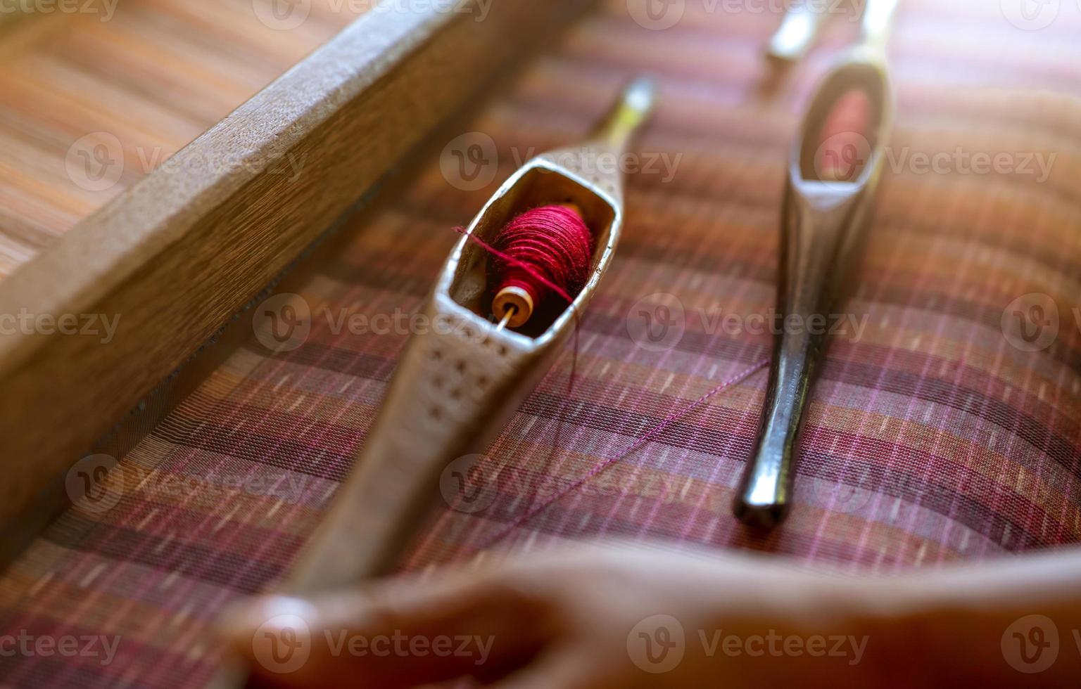 Woman working on weaving machine for weave handmade fabric. Textile weaving. Weaving using traditional hand weaving loom on cotton strands. Textile or cloth production in Thailand. Asian culture. photo