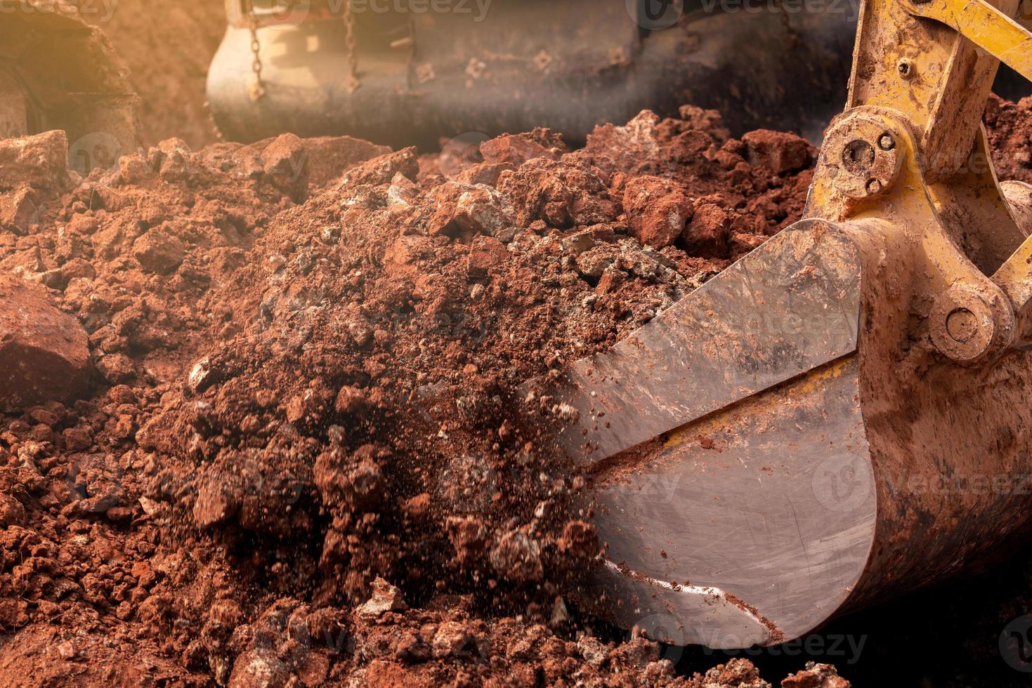 Closeup bucket of backhoe digging the soil at construction site. Crawler excavator digging on demolition site. Excavating machine. Earth moving equipment. Excavation vehicle. Construction business. photo