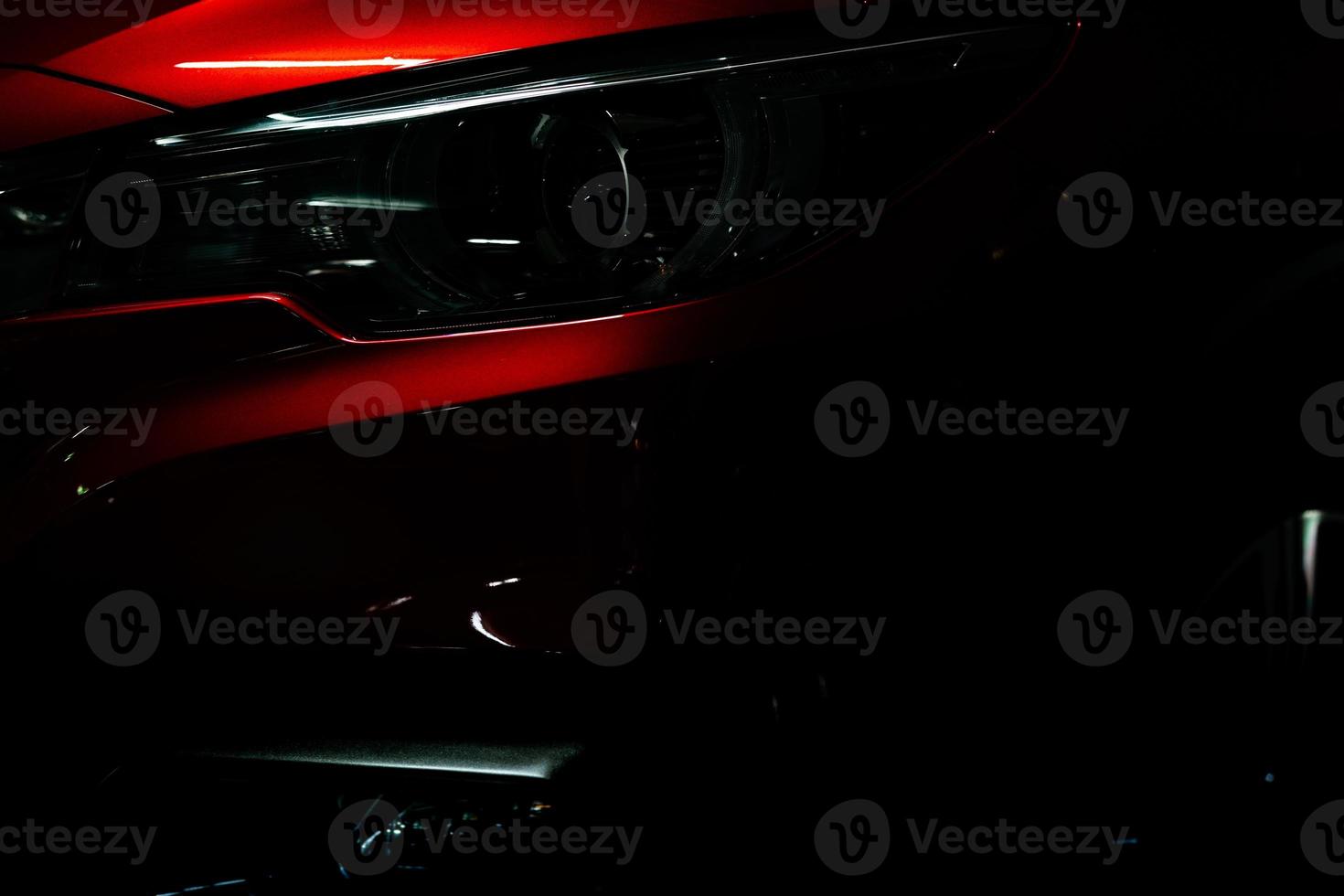 Closeup headlight of shiny red luxury SUV compact car. Elegant electric car technology and business concept. Hybrid auto and automotive concept. Car parked in showroom or motor show. Car dealership. photo