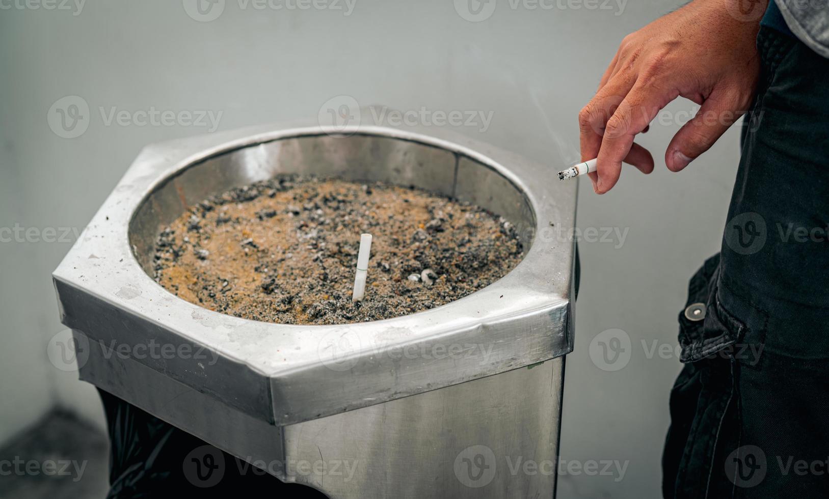 Closeup hand of a man with cigarette. People smoking in smoking zone area of the mall and left cigarette in ashtray. Quit smoke or smoking cessation and lung cancer. 31 May  World no tobacco day. photo