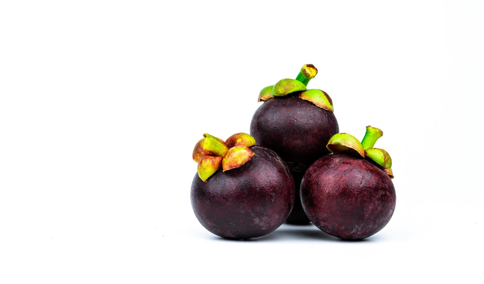 Whole mangosteen showing purple skin isolated on white background with space. Tropical fruit from Thailand. The queen of fruits. Asia fresh fruit market concept. Natural source of tannin and xanthones photo