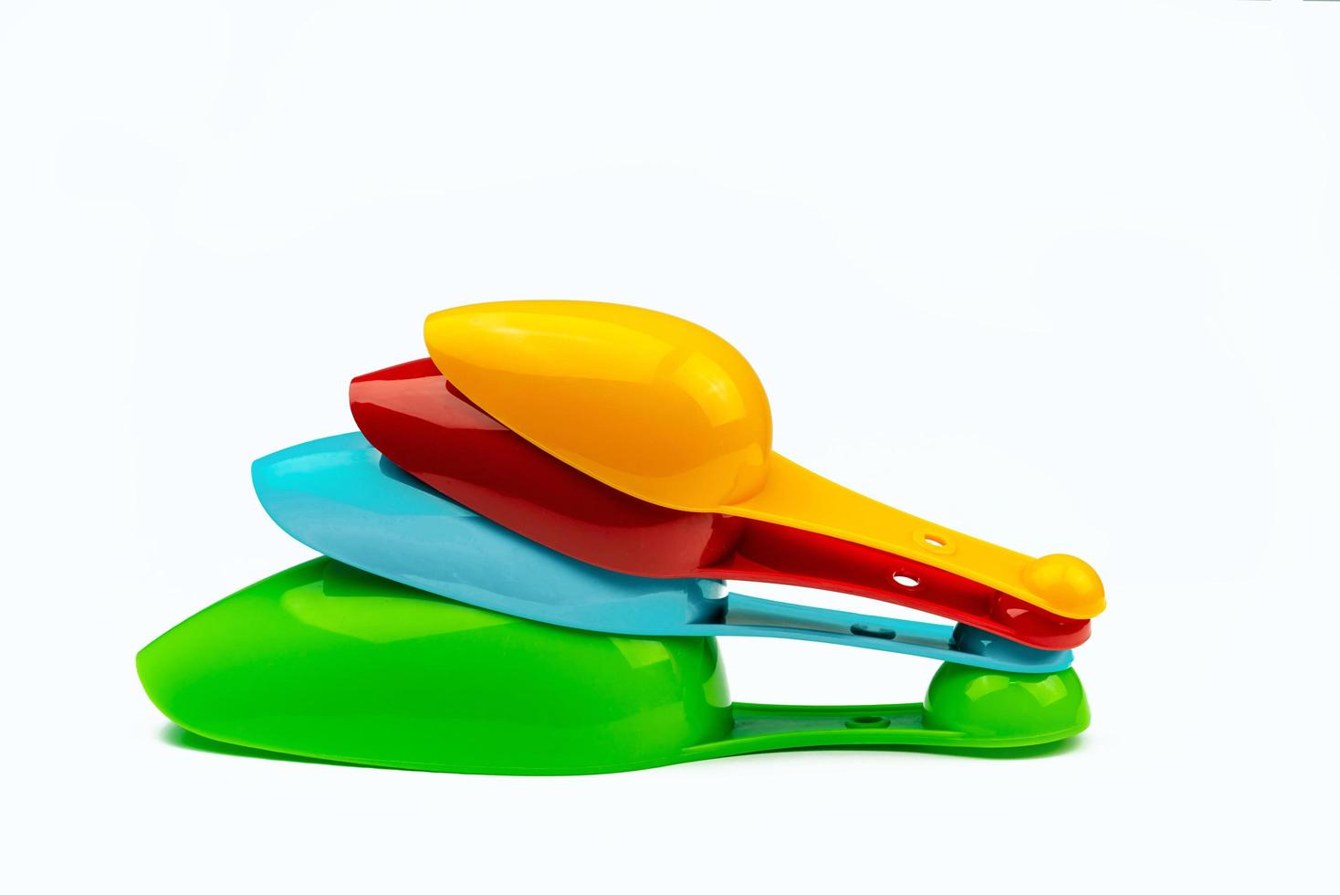 Set of colorful plastic measuring spoon isolated on white background with shadow. Green, blue, red, and orange plastic measuring spoon. photo